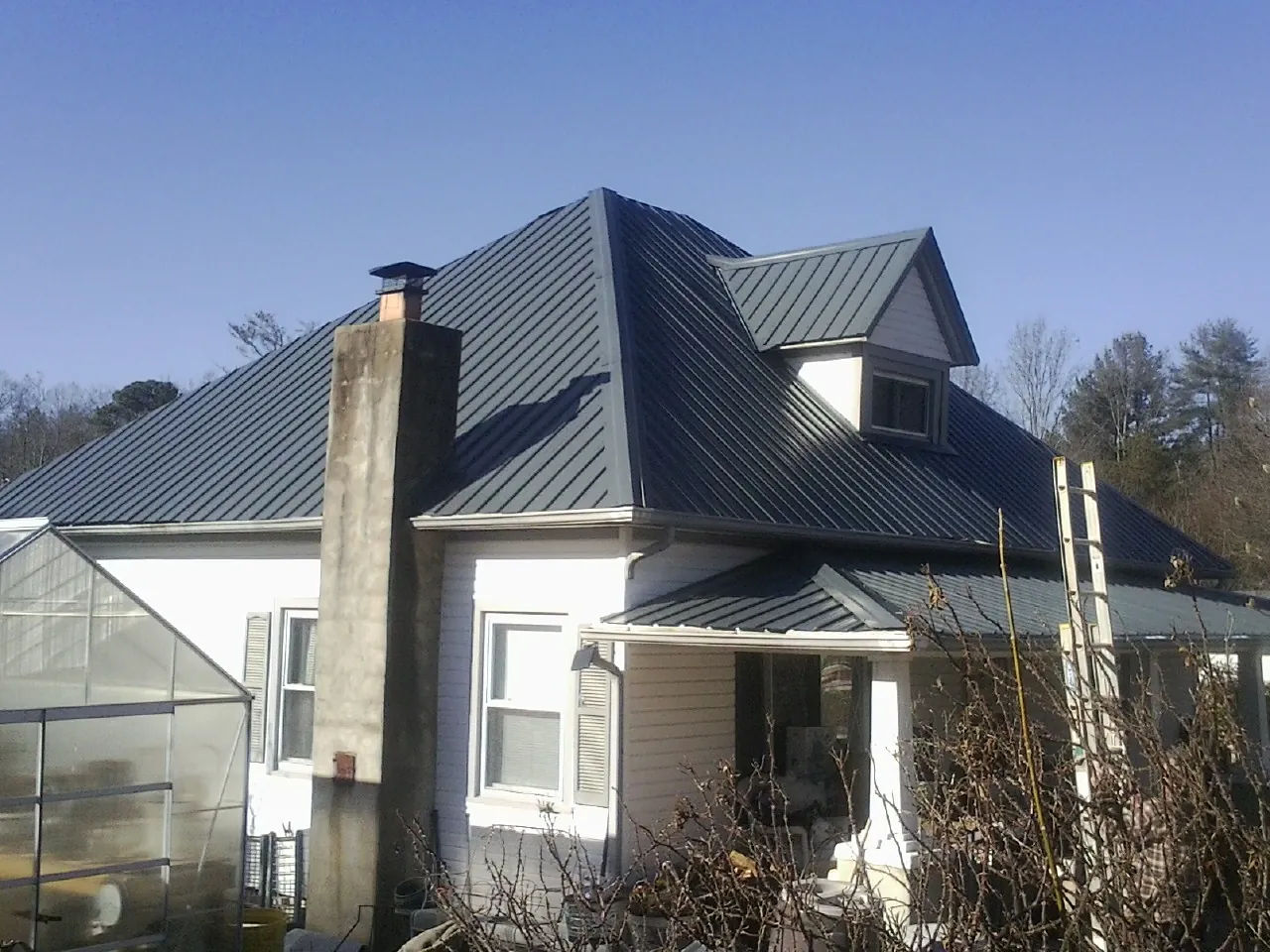 Dark blue standing seam metal roof on a white farmhouse with dormer — Slate & Tile Roof Repair by Roofing Brothers in Wallowa