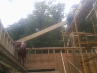 Carpenter raising a rafter beam on a new second story frame in Wallowa