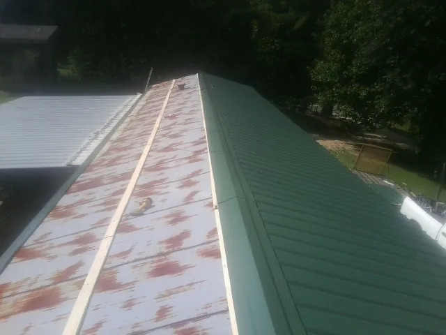 Old rusted panels beside newly installed green metal roofing — Wind Damage Roof Repair by Roofing Brothers in Wallowa