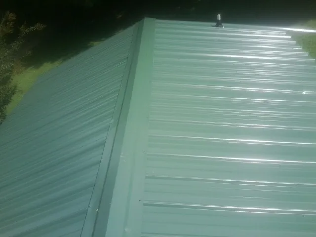 New green metal panels meeting at the ridge of a roof — Flat Roof Repair work by our crew in Wallowa