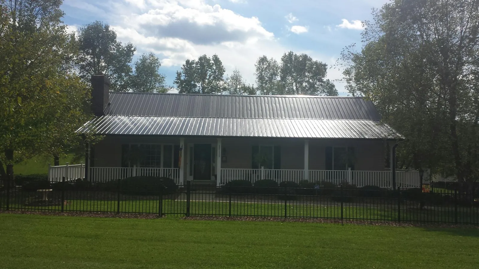 Gray metal roof on a brick ranch with a full width front porch — Gutter Guard Installation work by our crew in Wallowa