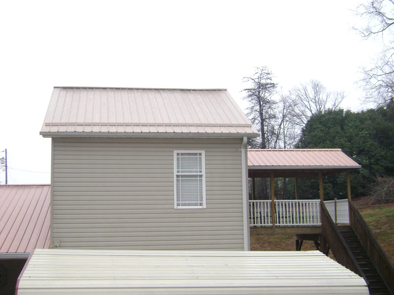 Tan metal roofs on a two story addition and attached porch, from a Roof Replacement job in Wallowa
